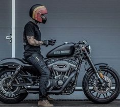 a man sitting on his motorcycle in front of a garage door wearing a helmet and gloves