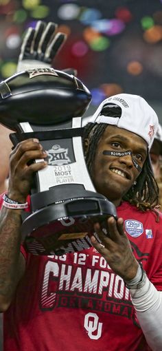 a man holding up a trophy in front of his face at a sporting event with other people around him