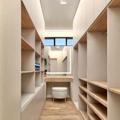 a walk in closet with lots of wooden shelves and shelving units on both sides