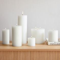 several white candles sitting on top of a wooden table