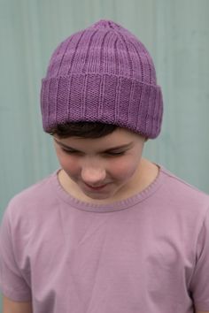 a young boy wearing a purple knitted hat