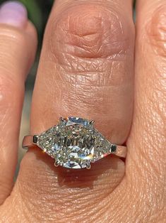 a woman's hand with a diamond ring on top of her finger and an engagement ring in the middle