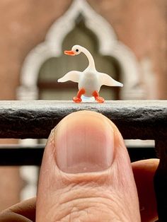 a small toy duck sitting on top of a finger