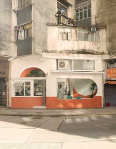 an orange and white building sitting on the side of a road next to tall buildings