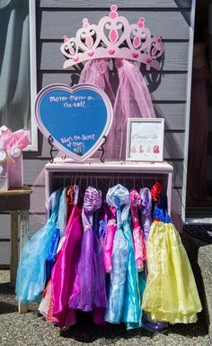 there are many princess dresses on display in front of the house with a heart shaped mirror