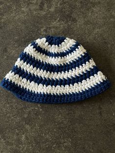 a blue and white crocheted hat laying on the ground