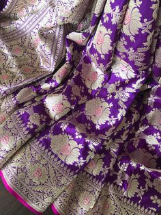 This is an authentic handloom kadhuwa jungla floral jaal banarasi saree woven in double katan silk. This splendid saree woven in purple colour is truly breathtaking!!Floral jaal woven in kadwa weave, which requires more skill and takes much longer to weave, makes this saree truly special. The meenakari floral motifs against the purple tone shines like an embossed jewel. Saree has fuschia pink selvedge on the borders which gives the subtle contrast. The same fuschia pink tone is used to accentuat Purple Banarasi Silk Traditional Wear With Pallu, Purple Banarasi Silk Traditional Wear For Puja, Purple Katan Silk Traditional Wear For Puja, Purple Katan Silk Traditional Wear For Diwali, Diwali Purple Katan Silk Traditional Wear, Purple Banarasi Silk Traditional Wear, Purple Paithani Silk Saree With Zari Weaving, Traditional Purple Banarasi Silk Saree, Festive Purple Banarasi Silk Traditional Wear