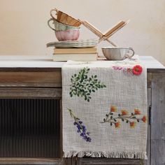 a table topped with plates and cups on top of a wooden dresser next to a book