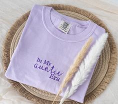 a t - shirt with the words in my country era written on it and a feather laying next to it