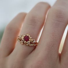 This epic ring is inspired by the Goron's Ruby in the Legend of Zelda: Ocarina of Time. On either side are super tiny dodongos holding the settings for accent diamonds. CUSTOMIZE GEMSTONES ✶ solid 14 karat recycled yellow, white, or rose gold✶ band measures 1.6mm wide x 1.4mm thick✶ natural center stone: 0.29 ct. A grade princess cut ruby✶ lab-grown center stone: 0.29 ct. princess cut lab-grown ruby✶ accent stones: 0.04 tcw. VS clarity round brilliant cut conflict-free diamondsThis ring will be Gold Ring Ruby Stone, Gold Ring With Ruby Stone, Ruby And Gold Ring, Gold And Ruby Ring, Wedding Ring Ruby, Fantasy Engagement Rings Ruby, Gold Ruby Ring, Ruby Wedding Ring, Intricate Ruby Ring Jewelry