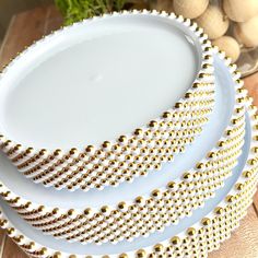 three white plates with gold beading on them