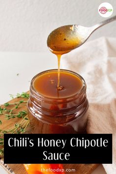 a spoon pouring honey into a jar filled with sauce