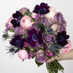 a bouquet of purple and white flowers in someone's hand