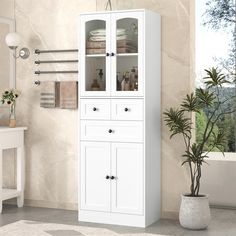 a tall white cabinet with glass doors in a bathroom next to a potted plant