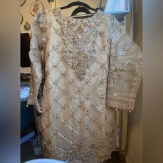 A Beautiful Gold Wedding Dress. Perfect For The Bride Or Bridal Party. Bodice Is Hand Beaded And Sewn With Paisley Motifs Throughout. The Shirt Is Lined But The Sleeves Are Not. The Bust Size Is 36n Inches, Sleeves Are 20-21 Inches, Waist Is 30-32 Inches And Elastic And The Gharara Pant Length Will Fit Anyone Who Is 5’2-5’6”. It Comes With A Dupatta And Long, Flowy Gharara Pants. All Thread Work Is Lined And Overlocked. Brand New And Unworn. Note: Any Defects Not Mentioned But Visible In The Pic Elegant White Wedding Dress For Eid, Silk Wedding Dress With Dabka Work, Fitted White Wedding Dress With Dupatta, Elegant White Wedding Dress With Resham Embroidery, Wedding Dresses In Organza With Dabka Work, Silk Wedding Gown With Dabka Work, White Hand Embellished Formal Gown, Elegant Wedding Dress With Dabka Work For Festive Occasion, Intricate Embroidery Mother Of The Bride Dress For Wedding