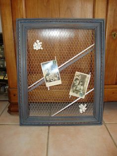 a chicken wire frame with photos and pictures in it on the floor next to a cabinet