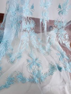 the sheer fabric has been embroidered with blue and white flowers on it, along with an intricate lace edge