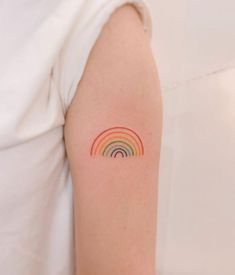 a person with a rainbow tattoo on their arm and behind her is a white shirt