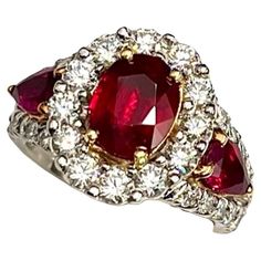 This is an absolutely stunning ring. It features a Natural 2.04Ct Oval Burmese Ruby flanked by 2 Natural Pear Shape Burmese Rubies of 1.00Ct Total Weight and 38 Natural White Round Brilliant Diamonds of 1.02Ct Total Weight. High quality Burmese Rubies such as this one are very sought after and valued. The color on this Ruby is a deep and rich red and the distribution of color is even. The stone is very vibrant and alive. The design of this ring is unique and will attract the discerning eye. White Gold Ruby Ring, Burmese Ruby, Contemporary Ring, Ruby Ring, Burmese, Pear Shape, Cocktail Rings, Pear Shaped, Round Brilliant