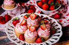 cupcakes with pink frosting and strawberries on a plate