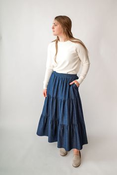 Perfect for a spring picnic or an everyday morning, the 'Celeste' skirt is so lovely and versatile! Constructed from lightweight cotton denim for a comfortable fit that moves with you, this skirt features hidden side pockets and an elastic waistband. Falling in ankle-length tiers, this comfortable skirt will compliment any simple top. Fit: true to size! Style: functioning pockets, elastic waist, tiered Color: dark wash Fabric content: 100% cotton Care instructions: wash gentle cycle, cold; lay f Tiered Skirt Outfit, Spring Picnic, Comfortable Skirts, Be Intentional, Simple Top, Modest Clothing, Garment Labels, Curated Gifts, Tier Skirt