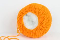 an orange crocheted object with a white hole in the center on a white background