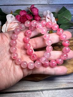 Stone: Icy Rhodonite Sakura Bead Shape: Round Colors: Pinks Light Pink 10mm (1)  Light Pink 11.2mm (1)  Light Pink 11.7mm (1)  Dark Pink 10.5mm (1) *sold out Bracelet is elastic and will stretch to accommodate most wrist sizes! Rhodonite helps to balance the emotions and calm impatience. Rhodonite is a very supportive stone that works with the Heart Chakra to attract love and ground negative energies. Rhodonite allows one to see areas in their life that can be improved on without getting down on Pink Gemstone Crystal Bracelet, Pink Natural Stones Crystal Bracelet, Pink Crystal Gemstone Bracelet, Pink Round Crystal Gemstone Bracelet, Healing Beaded Bracelets With Round Beads For Valentine's Day, Pink Hand-strung Round Crystal Bracelet, Pink Hand-strung Crystal Bracelet, Pink Round Spiritual Beaded Bracelets, Pink Beaded Jewelry With 8mm Round Beads