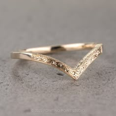 a close up of a gold ring on a gray surface with an intricate design in the middle