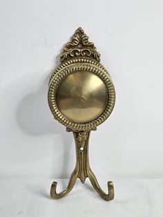 an antique brass clock on a stand against a white background