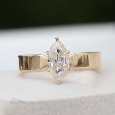 a close up of a ring with a large diamond on the front and side, sitting on a white surface