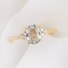 a ring with an oval cut stone surrounded by smaller round stones and gold trimmings