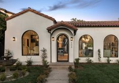 a white stucco house with arched windows and an entry way leading to the front door