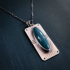 This necklace holds a beautiful piece of Leland Blue, found on the shores of Lake Michigan. Leland Blue is actually not a stone, but rather a byproduct of the smelting process of the 1800s in Michigan. When the smelting industry went bust, they dumped heaps of slag into Lake Michigan. Over years it has tumbled into beautiful blue beach-stone-looking pieces. I love that something ugly has turned into something beautiful. People now comb the beaches hunting for this coveted Leland Blue. This necklace represents how we can turn lemons into lemonade. The necklace is sterling silver and measures approximately 1.5" long and .6" wide. It hangs on an 18" sterling silver chain. If you would like a longer or shorter chain, please write a note at checkout. The necklace is handcrafted in my jewelry st Blue Necklace With Large Rectangular Pendant, Antique Blue Gemstone Necklaces, Antique Blue Jewelry With Large Pendant, Antique Blue Sterling Silver Necklace, Artisan Blue Jewelry With Cabochon, Antique Blue Oval Pendant Necklace, Artisan Blue Cabochon Jewelry, Collectible Oval Necklace With Large Stone, Blue Oval Pendant Collectible Jewelry