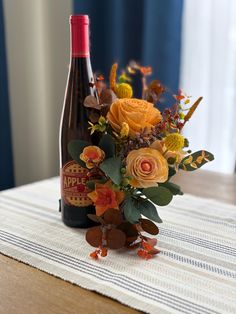 a bottle of wine sitting on top of a table next to a vase filled with flowers