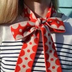 a woman wearing a red and white polka dot scarf with a large bow on her neck