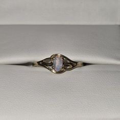 an opal stone is set in the center of a gold ring on a white leather surface