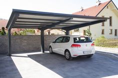 a white car is parked in front of a gray wall with a black awning