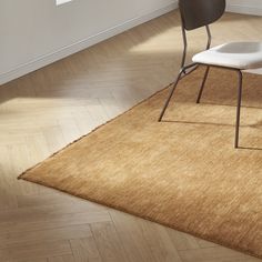 a white chair sitting on top of a wooden floor next to a brown and white rug