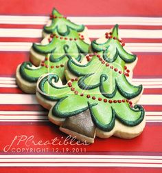 three decorated christmas tree cookies sitting on top of a table