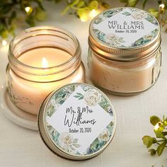 two jars filled with candles sitting next to each other on a white cloth covered table