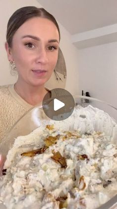 a woman is holding a large bowl of food in front of her face and talking to the camera