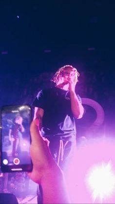 a person holding up a cell phone in front of a crowd at a music concert