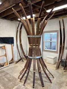 a sculpture made out of wooden sticks in a room with exposed ceiling beams and windows