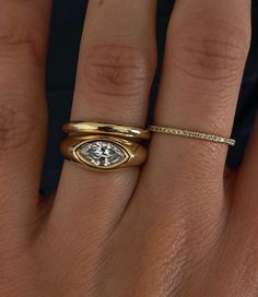 a woman's hand with a gold ring and diamond on the middle finger,