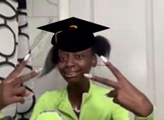 a woman wearing a graduation cap and holding up two fingers