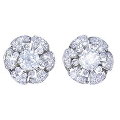 A beautiful pair of vintage platinum diamond earrings from the roaring 1930s. While designed as classic cluster earrings, this Art Deco inspired platinum diamond pair features unique details. Resembling a flower, each earring features in the center an antique cushion cut diamond, also called Old Mine cut. These two diamonds come with GIA Diamond Grading Reports (see pictures 6 and 7). The "flower’s petals” are skillfully crafted out of folded platinum and embellished with diamonds. Between the p Luxury Platinum Cluster Earrings With Diamond Cut, Luxury Single Cut Diamond Cluster Earrings For Engagement, Luxury Classic Lab Grown Diamond Cluster Earrings, Luxury Elegant Lab-grown Diamond Cluster Earrings, Timeless Luxury Diamond White Cluster Earrings, Luxury Silver Platinum Cluster Earrings, Luxury Timeless Diamond White Cluster Earrings, Antique Cushion Cut Diamond, Antique Cushion Cut