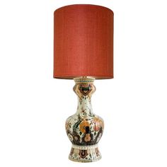 a table lamp with a red shade on it's base and an ornate design