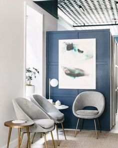 a living room filled with furniture and paintings on the wall next to two chairs in front of a painting