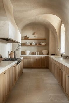 a long narrow kitchen with wooden cabinets and white counter tops, along with an arched ceiling