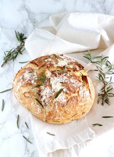 bread with herbs on it sitting on top of a white cloth next to some napkins